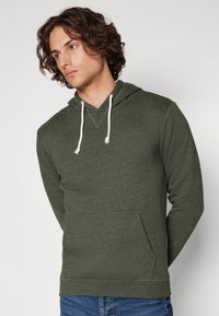 Sudadera con capucha de color verde oscuro, con bolsillo tipo canguro, cordones y una tela texturizada. Corte casual, mangas largas y puños acanalados.