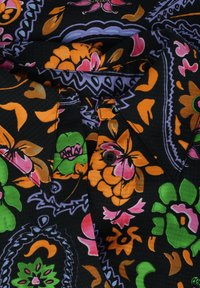 Zwarte stof met een bloemenpatroon in oranje, roze, groen en paars. Bevat een kraag en knoopsluitingen.