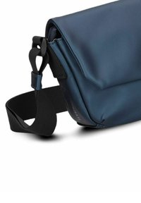Borsa a spalla sintetica blu con chiusura a pattina, tracolla nera regolabile e texture liscia. Dettaglio del logo ben visibile sul lato.