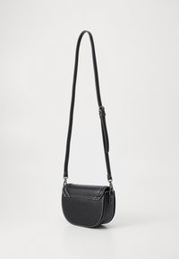 Bolso cruzado de cuero negro con forma redondeada, costuras blancas en contraste y una correa ajustable. Presenta un cierre de solapa y una textura suave.