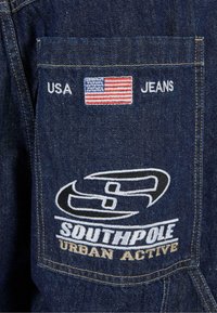 Tumed denim teksased, millel on tikitud Ameerika lipp, "USA" ja "JEANS" tagakotil. Omab "SOUTHPOLE URBAN ACTIVE" logo disaini.