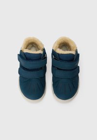 Chaussures en cuir bleu pour tout-petits avec deux bandes velcro, doublure en fourrure crème, semelle en caoutchouc et détails de couture subtils.