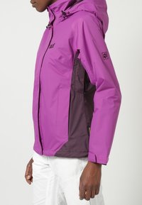 Chaqueta impermeable morada con cremallera frontal, capucha ajustable y paneles laterales en tono púrpura oscuro. Textura suave, diseño ligero.