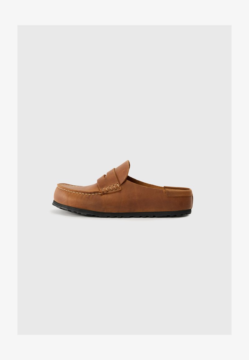 Brown leather slip-on shoe with rounded front, visible stitching, and rubber sole. Smooth texture and minimalist design.