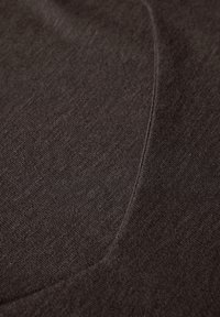 Tummanruskea kangas, jossa on pehmeä rakenne, joka näyttää hieman kiiltävältä ja jossa on kaareva sauma. Materiaali vaikuttaa kevyeltä ja sileältä.