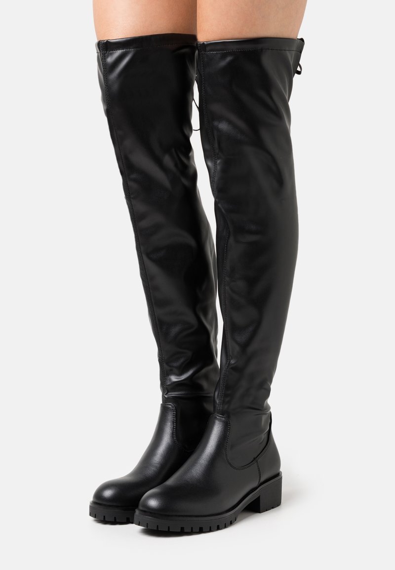 Botas altas de imitación piel negra con una textura suave, tacón bloque y detalles de costura. Presentan un diseño de fácil calzado y punta redondeada.