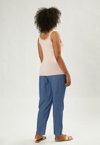 Top sin mangas rosa con encaje, combinado con pantalones sueltos de color azul claro. El conjunto presenta un diseño sencillo y texturas suaves.