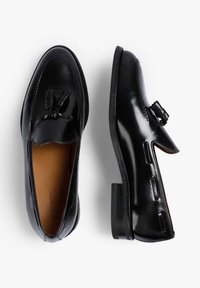 Mocasines de cuero negro con un acabado suave, que cuentan con un detalle decorativo de lazo, un tacón bajo y un diseño de punta redondeada.