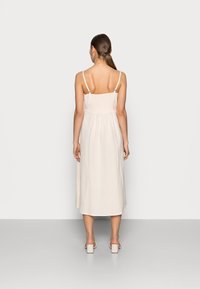 Hellbeige ärmelloses Kleid mit tailliertem Oberteil, gerafftem Rücken und fließendem Rock. Es hat dünne Träger und einen knielangen Saum.