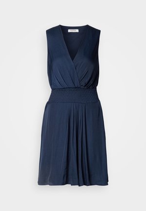 Robe sans manches bleu marine avec décolleté en V profond, taille smockée et jupe évasée. Fabriquée en tissu doux, avec une texture subtile.