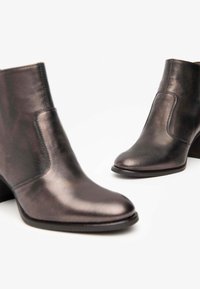 Bottines en cuir gris foncé avec une texture lisse, bouts arrondis et un talon carré de hauteur moyenne. Couture renforcée le long des bords.