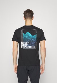 Svart bomull t-shirt med en grafik av gröna och blå berg samt texten "NEVER STOP EXPLORING" på ryggen. Kort ärm, standard passform.