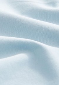 Vaaleansininen kangas, jossa hienovarainen tekstuuri ja hienojakoinen poikkijuovitus, esittelee sileää laskeutuvuutta ja pehmeitä laskoksia. Pehmeä, joustava materiaali.