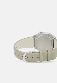 Montre octogonale avec un boîtier en métal argenté et un bracelet en cuir gris clair. Dispose d'une boucle simple et de plusieurs trous de réglage pour s'adapter à la taille.