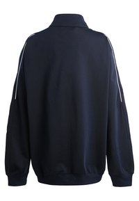 Sweatshirt bleu marine avec col haut, manches longues et rayures blanches sur les côtés. Tissu doux et poignets côtelés. Design épuré et simple.