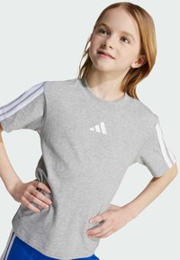 Camiseta de algodón gris de manga corta, con tres rayas blancas en los hombros y un pequeño logotipo bordado en el pecho.