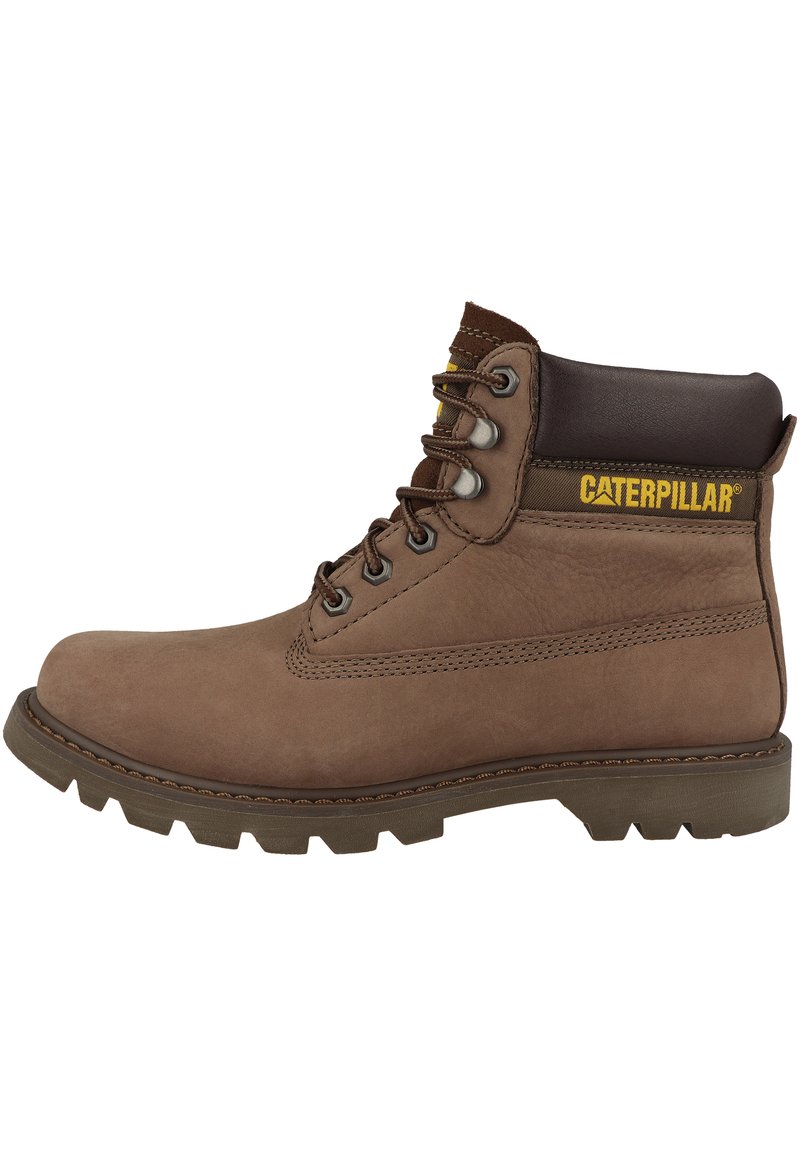 Bota de tobillo de cuero marrón con suela de goma, presenta ojetes metálicos, un cuello acolchado y un logo amarillo de Caterpillar en el lateral.