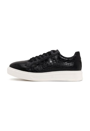 Sneaker nera a taglio basso con texture in coccodrillo e lacci neri, abbinata a una spessa suola in gomma bianca.