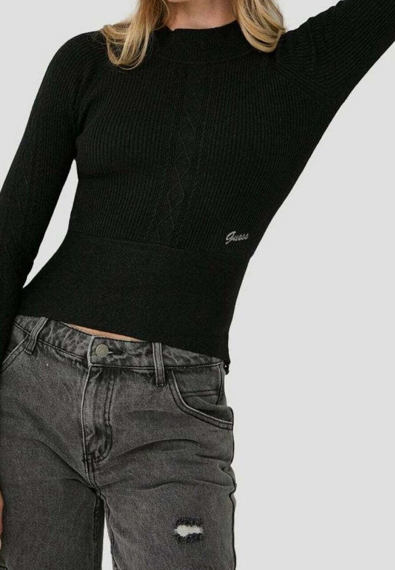 Schwarzer gerippter Pullover mit hohem Kragen und Zopfmuster. Kombiniert mit ausgewaschenen grauen Denim-Jeans mit fransiger Tasche.