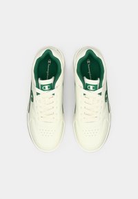 Λευκά αθλητικά παπούτσια με λείο δερμάτινο φινίρισμα, πράσινες λεπτομέρειες στα πλαϊνά και διάτρητο μπροστινό μέρος. Περιλαμβάνει επίπεδα κορδόνια και λογότυπο στη γλώσσα του παπουτσιού.
