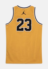 Żółta koszulka do koszykówki z siateczkowego materiału, z czarnym napisem "23" oraz logo Jumpman. Posiada białe wykończenie wzdłuż dekoltu i otworów na ramiona.