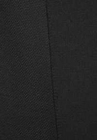 Černá látka se dvěma texturami: jedna hladká a druhá s jemným mřížkovým vzorem. Barva je jednotná a konzistentní po celé ploše.