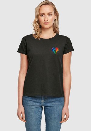 Black cotton t-shirt featuring a colorful rainbow heart design on the left chest. Short sleeves, crew neck, relaxed fit.