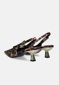 Zapatos de tacón stilettos con estampado de leopardo y punta afilada, parte superior de tela y detalles en tono dorado. El tacón sculptural tiene una base negra.