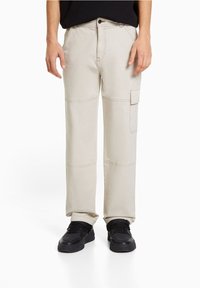 Beige cargo pants with a straight leg design, patch pockets on the side, made of durable cotton blend, featuring stitched accents.