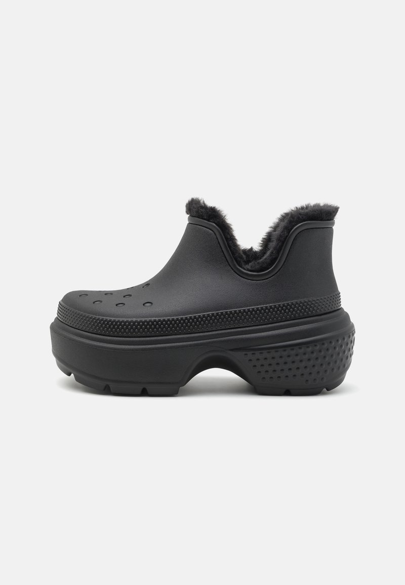 Sabot à plateforme noire avec semelle texturée, trous de ventilation sur le dessus et doublure en fourrure noire moelleuse autour de la cheville.