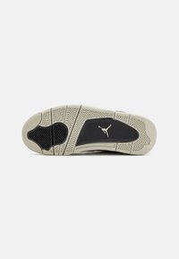 Suela de zapato con base de goma, que presenta un patrón de espiga en negro y crema, y un logo en dorado en la zona del talón.