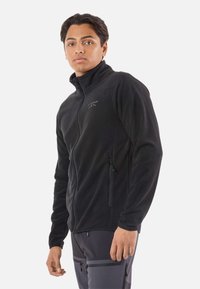 Zwarte fleece jas met een hoge kraag, ritssluiting aan de voorkant en zijzakken. Voorzien van een subtiel logo op de borst. Soepele textuur.