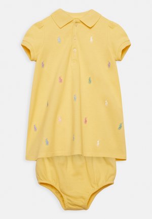 Żółta sukienka polo z krótkimi rękawami, ozdobiona haftowanymi wielokolorowymi kucykami. Zawiera wbudowaną pieluszkę dla wygody.