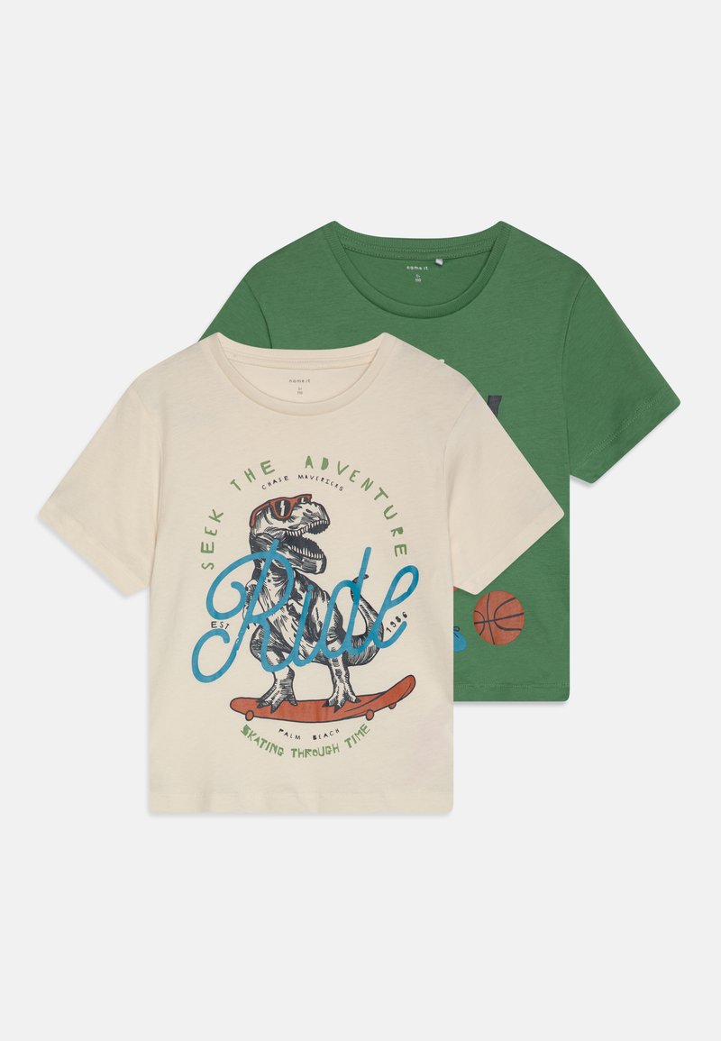 Dos camisetas de manga corta: una color crema con un gráfico de dinosaurio y texto, y otra verde que presenta un diseño de baloncesto. Material de algodón.