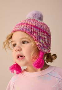 Gestrickte Mütze in lebhaften Pink- und Lilatönen, mit einem flauschigen Bommel und seitlichen Quasten. Strukturiertes Muster mit gemischten Garnfarben.