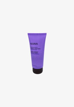 Lila Tube mit AHAVA Totes Meer Mineral Handcreme mit strukturierter Oberfläche, schwarzem Boden und weißen Sprenkeln; 100 ml Fassungsvermögen.