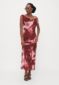 Bordový kvetinový off-shoulder šaty s priliehavým pásom a voľnou sukňou. Obsahuje jemné nariasenie a hladkú, ľahkú látku. Čierne sandále na remienky.