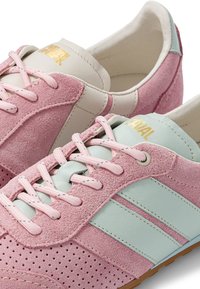 Baskets en cuir suédé rose et bleu clair avec des lacets roses, zone des orteils perforée et logo doré sur la languette.