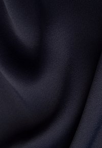 Tissu bleu marine foncé, lisse, avec des plis subtils et une texture fine tissée, créant des ombres douces et des reflets.