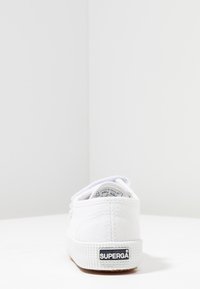Sneaker in tela bianca Superga vista da dietro, mostrando la suola testurizzata e il logo del marchio sul tallone.