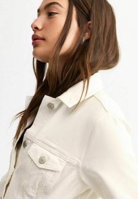 Krämfärgad denimjacka med krage, silverfärgade knappdetaljer och framfickor, med en slät textur och smal passform.