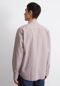 Camicia a maniche lunghe a righe verticali rosse e bianche, realizzata in cotone tessuto. Presenta un colletto classico e polsini con bottoni.