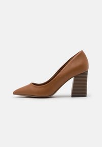 Chaussure à talon haut en cuir marron avec un bout pointu et un talon bloc épais à rainures. Texture lisse avec un design minimaliste.
