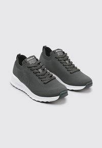 Zapatillas deportivas de color gris oscuro con parte superior de punto texturizado, diseño de cordones, mediopie en blanco y lengüeta con marca. Punta redondeada y suela flexible.