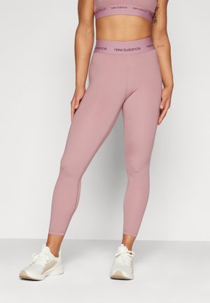 Leggings rosa chiaro con una vita alta, dotati di branding "New Balance". Realizzati in materiale elasticizzato, con una texture liscia e una forma aderente.