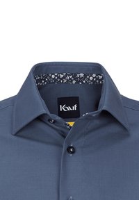 Camicia blu navy con particolare dettaglio a contrasto sul colletto interno. Presenta un colletto classico e un solo bottone sul petto.