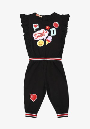 Sort jumpsuit med flæseærmer, prydet med farverige lapper (hjerter, emojis, isvafler), stribet talje og elastiske manchetter.