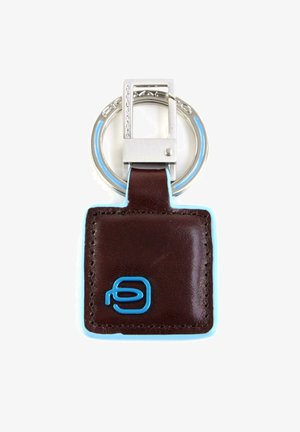 Portachiavi in pelle marrone con accenti azzurri, etichetta rettangolare e anello circolare in metallo argento. Logo impresso in blu sull'etichetta.