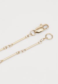 Gold-tone metal chain with interlocking oval links, featuring a lobster clasp on one end and a round keyring on the other.