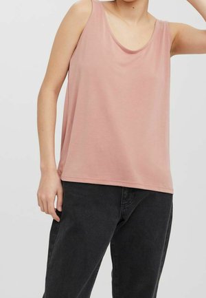 Jasnoróżowy na ramiączkach top bez rękawów wykonany z miękkiego materiału, z okrągłym dekoltem i luźnym krojem, skomponowany z ciemnoniebieskimi dżinsami.